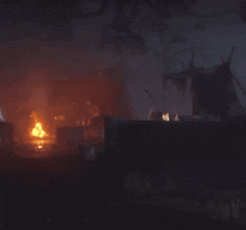 a man standing in front of a fire with his arms outstretched