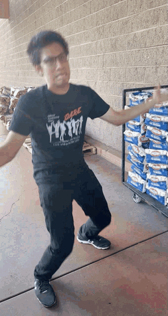 a man wearing a dare t-shirt is dancing in front of a cart of kraft macaroni and cheese