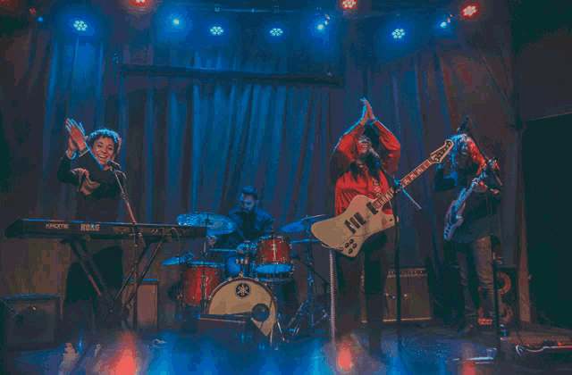 a group of people on a stage with a keyboard that says korg on it