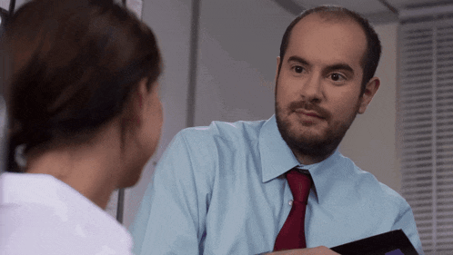 a man in a blue shirt and red tie talks to a woman in a white shirt