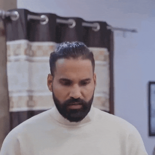 a man with a beard wearing a white sweater