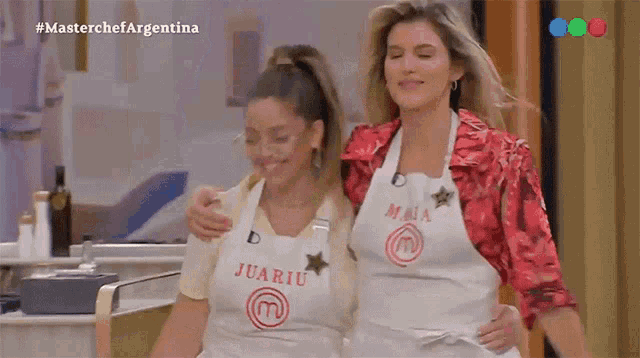 two women wearing aprons with the letter m on them are standing next to each other