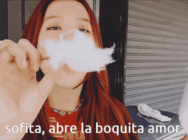 a woman blowing cotton candy with the words sofita abre la boquita amor