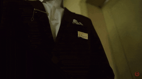 a man in a suit is standing in front of a door that has the number 50 on it