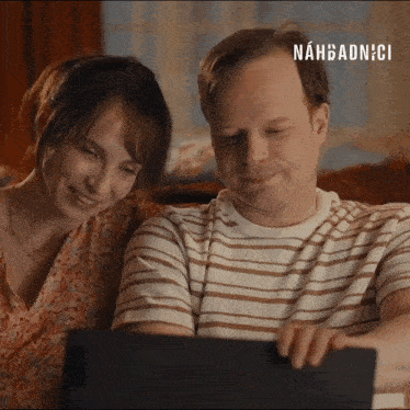 a man and a woman are looking at a tablet with nahbadnici on the bottom