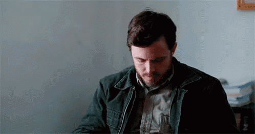 a man in a black jacket is sitting at a table with his eyes closed .
