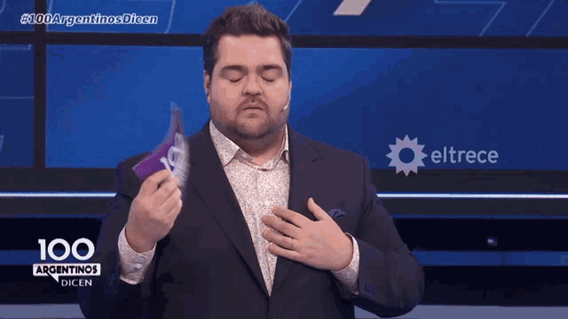 a man in a suit is holding a card that says 100 argentinas dicen