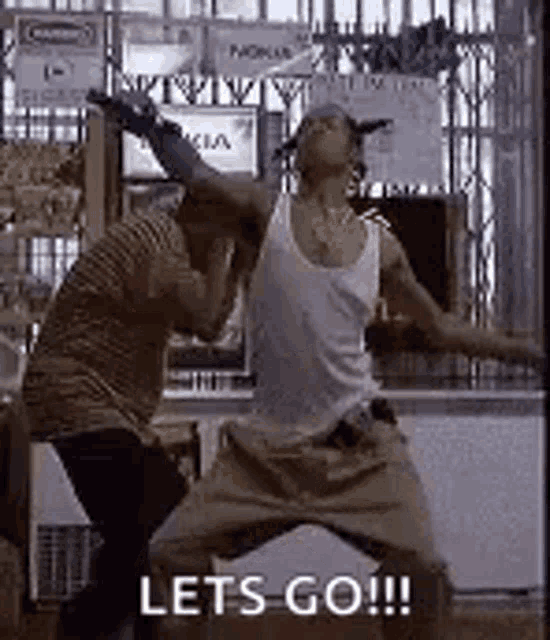 two men are standing next to each other in a store and dancing .