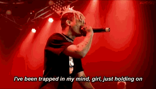 a man singing into a microphone with the words " i 've been trapped in my mind girl just holding on " next to him