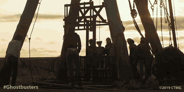 a group of people standing in front of a crane with the words ghostbusters written on the bottom