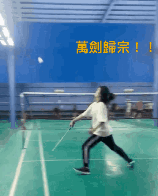 a person playing badminton on a court with chinese writing on the wall behind them