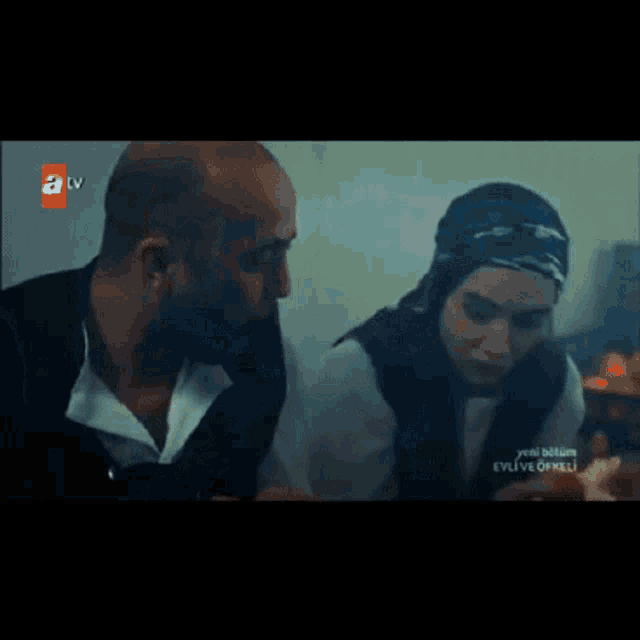 a man and a woman are looking into each other 's eyes with a tv advertisement behind them