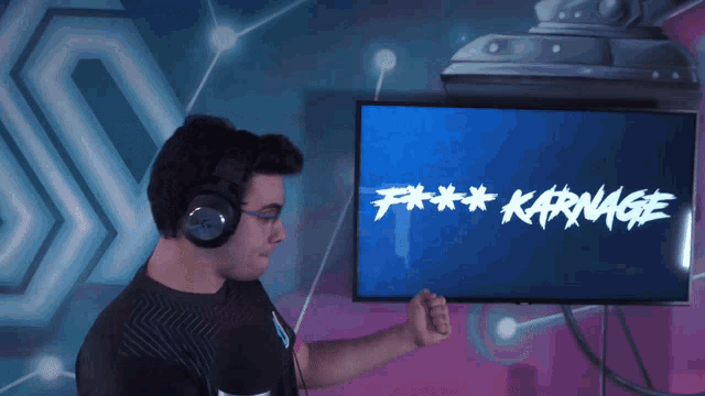 a man wearing headphones stands in front of a screen that says " f *** karnage "