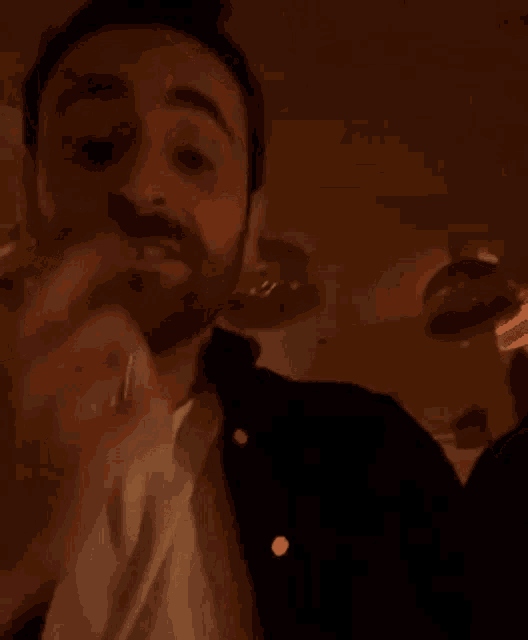 a man with a beard is singing into a microphone while wearing a black jacket .