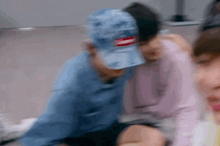 a blurry picture of a group of people sitting on the floor . one of the people is wearing a blue hat .