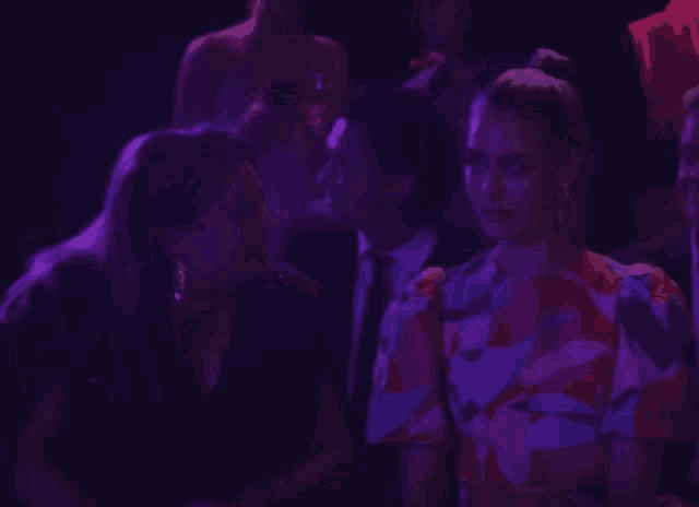 a woman in a floral dress talks to a man in a suit