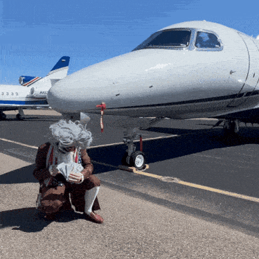 a man in a wig is kneeling in front of a plane with the number n4382 on the tail