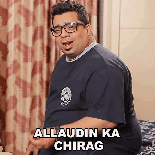 a man wearing glasses says allaudin ka chirag while sitting on a bed