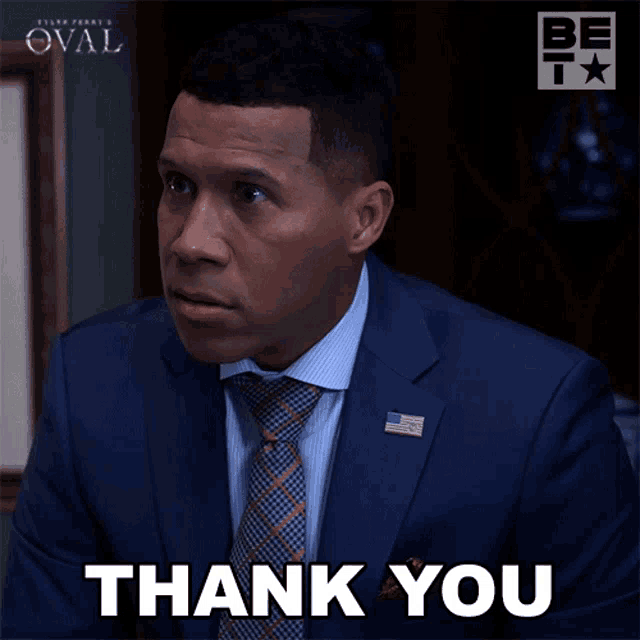 a man in a suit and tie is giving a thank you gesture