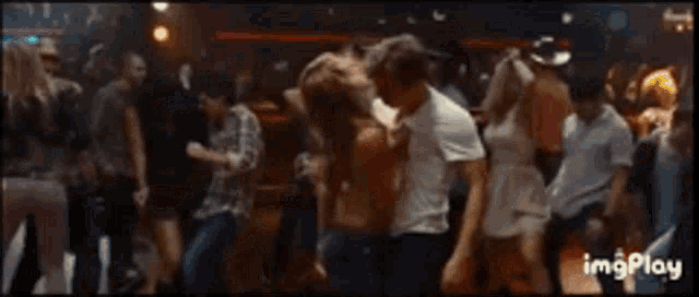 a man and a woman are dancing together in a crowded room .