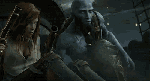 a man and a woman are standing next to each other and the man is holding a gun