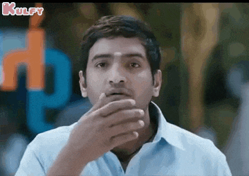 a man is covering his mouth with his hand while making a funny face .