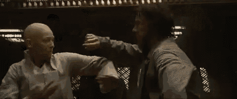 two men are standing next to each other in a dark room and fighting .