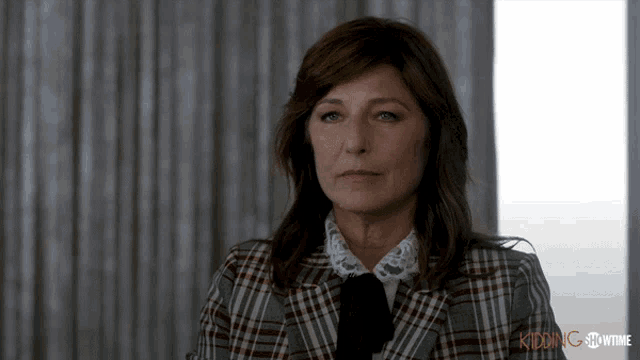 a woman is wearing a plaid jacket and tie with the words kidding showtime on the bottom right