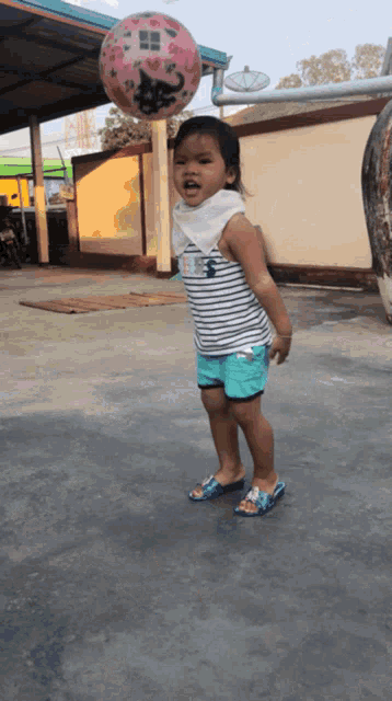 a little girl is playing with a ball that has a cat on it