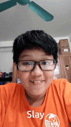 a young boy wearing glasses and an orange shirt with the word slay on it