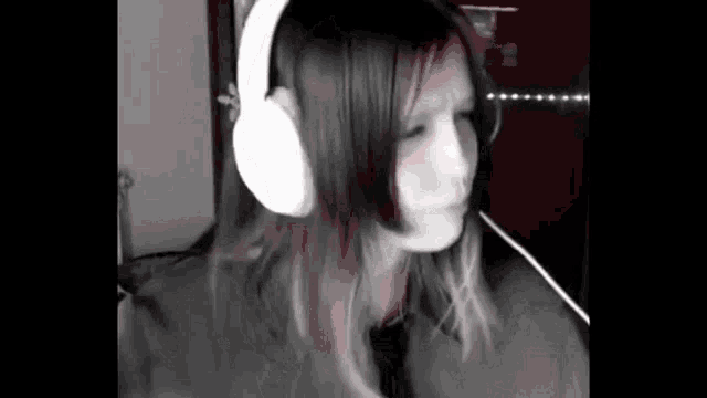 a woman wearing headphones is dancing in a black and white photo .