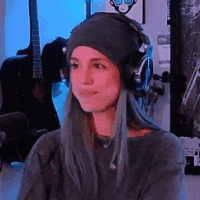 a woman with long blue hair is wearing headphones and a beanie .