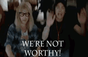 a man and a woman are raising their arms in the air with the words `` we 're not worthy '' behind them .
