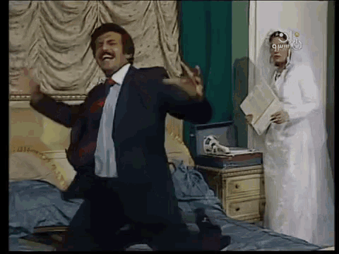 a man in a suit is dancing in front of a woman in a wedding dress