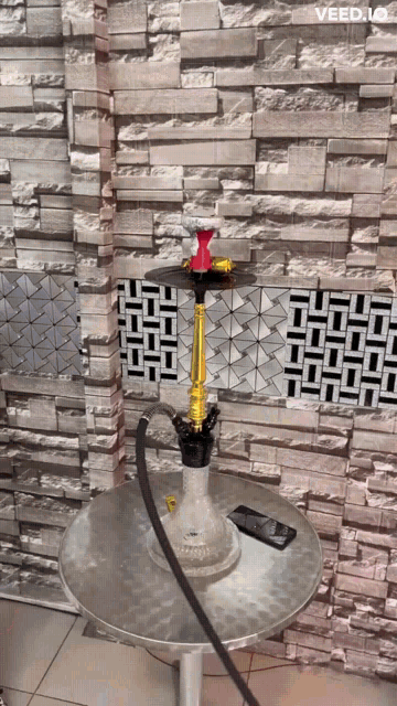 a hookah is sitting on a silver table in front of a brick wall