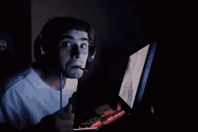 a man wearing headphones and a microphone is looking at a computer screen