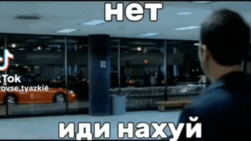 a man standing in front of a building with a car in the window and the words het in white