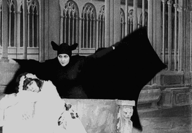 a black and white photo of a vampire and a woman in a white dress
