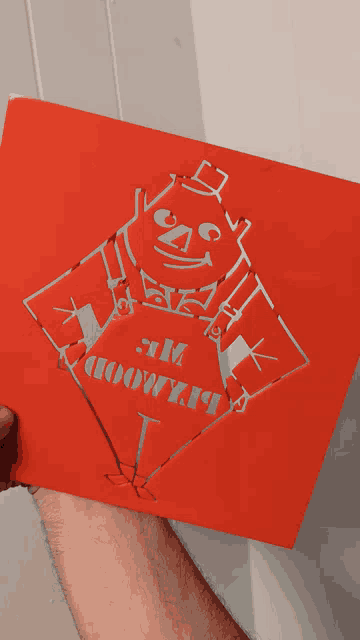 a person is holding a red piece of paper with a drawing of a man and the words " i am 100 % " on it