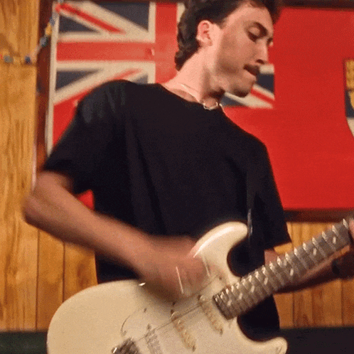 a man in a black shirt is playing a guitar