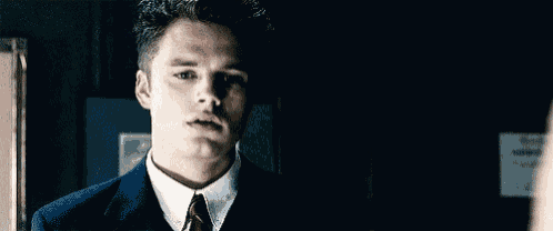 a man in a suit and tie is looking at the camera .