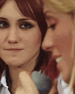 a close up of two women 's faces one with red hair