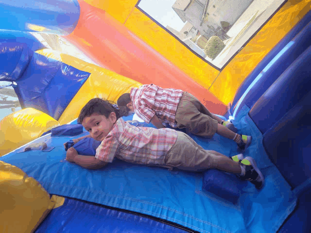 two young boys laying on a bouncy house