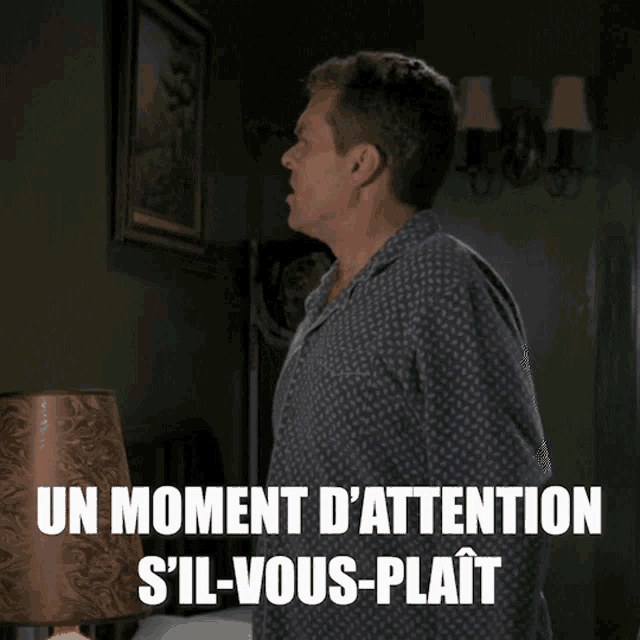a man standing in front of a lamp with the words un moment d' attention s'il-vous-plait
