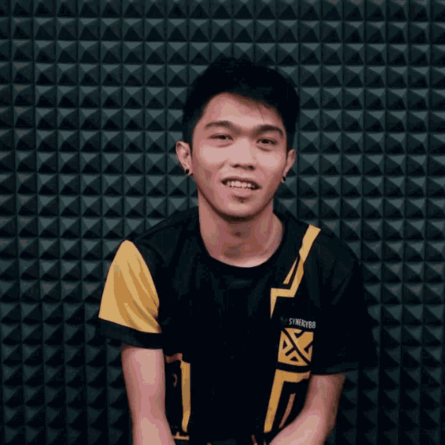 a young man wearing a black and yellow shirt that says synergy88