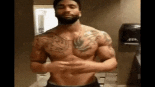 a shirtless man with a beard is standing in front of a mirror .