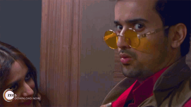 a close up of a man wearing sunglasses with a zees download now advertisement behind him