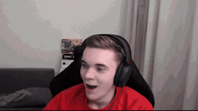 a man wearing headphones and a red shirt is sitting in a chair