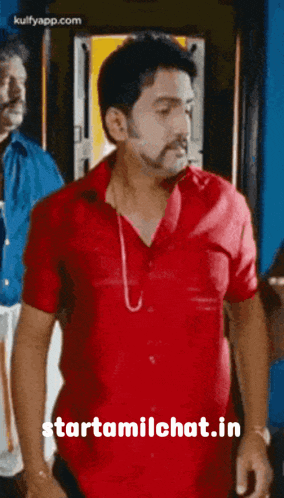 a man in a red shirt is standing in front of a sign that says " starttamilchat.in "