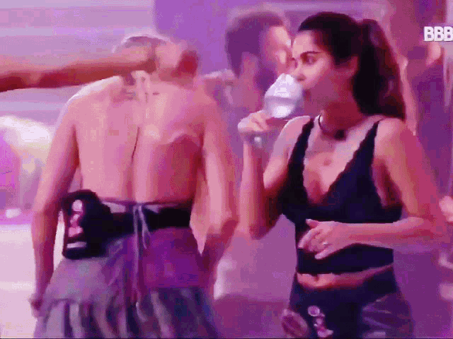 a woman in a black bra is drinking from a bottle
